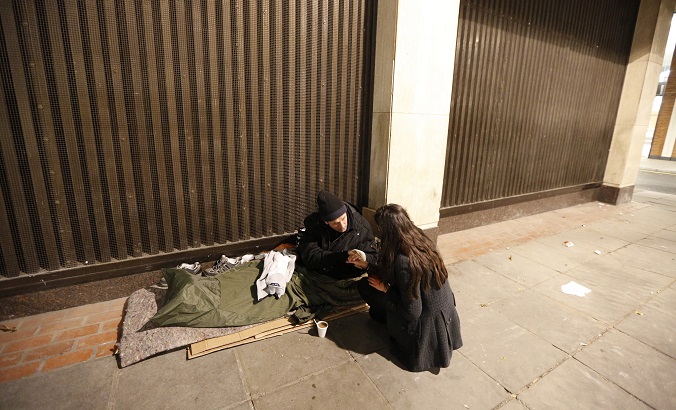 A homeless man grasps the hand of a volunteer, who was handing out donated clothing, near Victoria rail station in central London.
