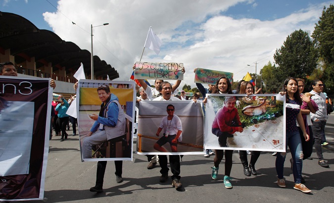 Relatives and friends hold pictures of Ecuadorean journalists who were kidnapped near the Colombian border, during a protest march to demand for their release.