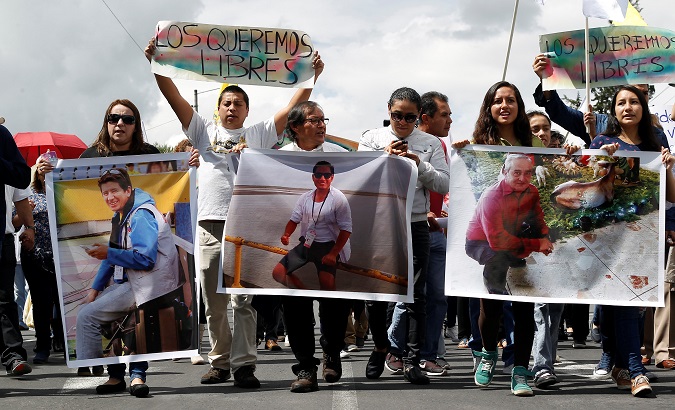 Relatives and friends hold pictures of Ecuadorean journalists who were kidnapped near the Colombian border, during a protest march to demand for their release, in Quito.