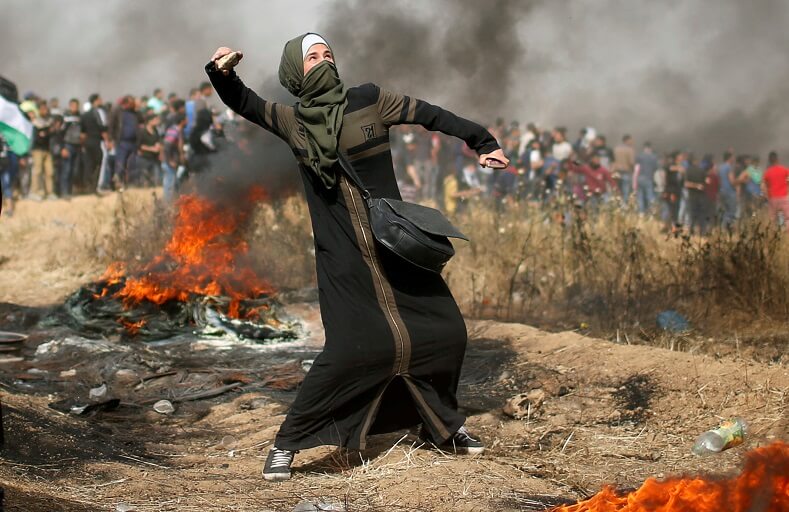 Woman hurls stone at Israeli snipers. 