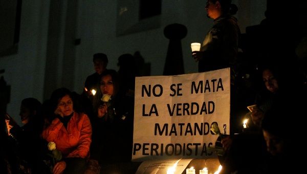 People participate in a vigil for two Ecuadorean journalists and their driver in Quito, Ecuador April 13, 2018. The sign reads, 