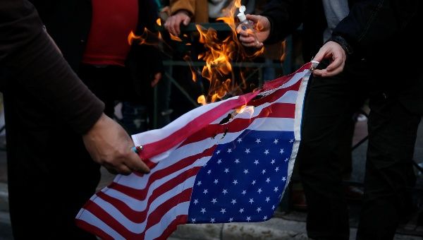 Protesters burn an U.S. flag during a demonstration outside the U.S. embassy against air strikes carried out in Syria, in Athens, Greece, April 14, 2018.