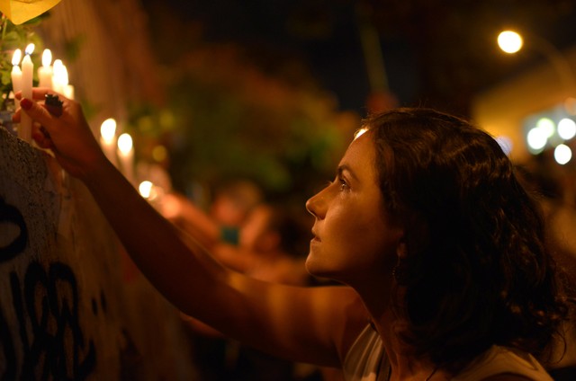 Demonstrators light candles on a wall, in front of the crime scene, as they take part in a protest against the shooting of Rio de Janeiro city councillor Marielle Franco one month after her death, in Rio de Janeiro, Brazil April 14, 2018