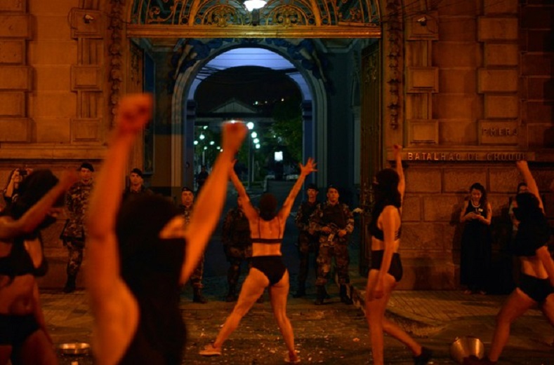 Demonstrators perform in front of a police battalion as they take part in a protest against the shooting of Rio de Janeiro city councillor Marielle Franco one month after her death, in Rio de Janeiro, Brazil 