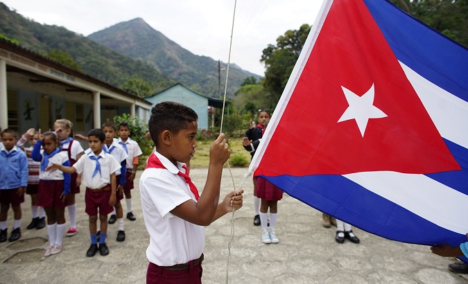 A boy raises the Cuban flag during a daily ceremony held at a school in the village of Santo Domingo, in the Sierra Maestra, Cuba, April 2, 2018.