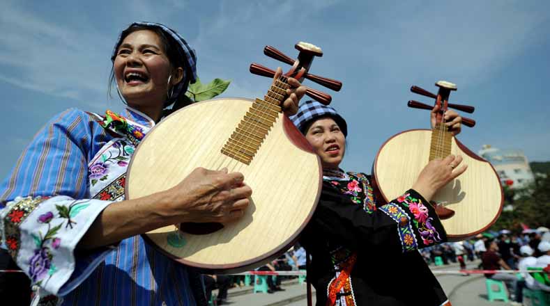 Además, varios locales tocan el yueqin, un instrumento parecido al banjo con cuatro cuerdas, en una celebración en el condado de Wangmo, provincia de Guizhou.