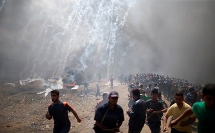Palestinian demonstrators run from tear gas fired by Israeli troops 