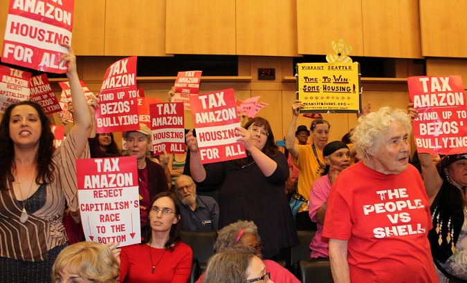 Protesters hold placards during a city council vote for a new tax on the city's biggest companies as a way of fighting a housing crisis sponsors attribute largely to a local economic boom driving real estate costs, in Seattle, Washington, U.S., May 14, 2018.