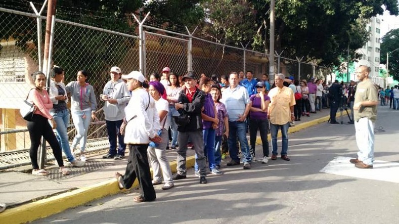 Venezuelans stand in queue outside a polling booth in Caracas' Andres Bello High School. 
