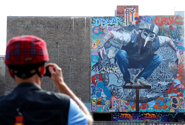 A man takes a picture of the artwork 'Kollabo Wand,' part of the first Berlin Mural Fest. 