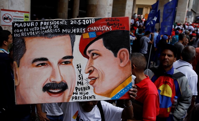 A supporter holds a painting of Venezuela's re-elected President Maduro next to the late President Chavez outside the National Electoral Council (CNE) in Caracas.