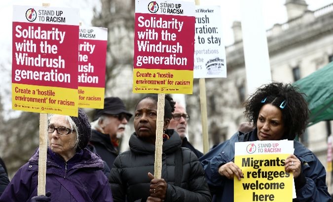 People hold placards during a demonstration to protest against the treatment of members of the Windrush generation in Britain.