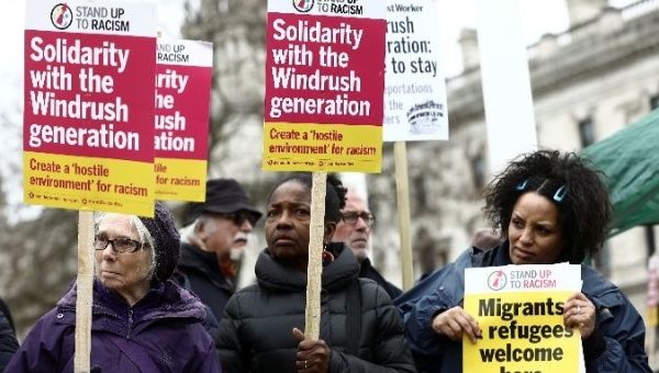 People hold placards during a demonstration to protest against the treatment of members of the Windrush generation in Britain.