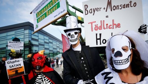 Protesters outside of Bayer's shareholders meeting carry a sign that reads 'Bayer + Monsanto = Deadly'