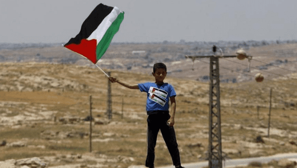 A Palestinian Bedouin boy holds a Palestinian flag during a protest against Jewish settlements in Susya village south of the West Bank city of Hebron.