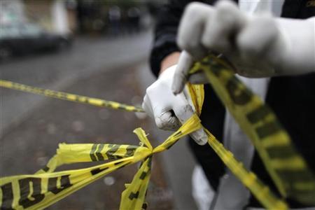 A forensic technician ties a used police line together to seal off a crime scene in Monterrey February 8, 2012.