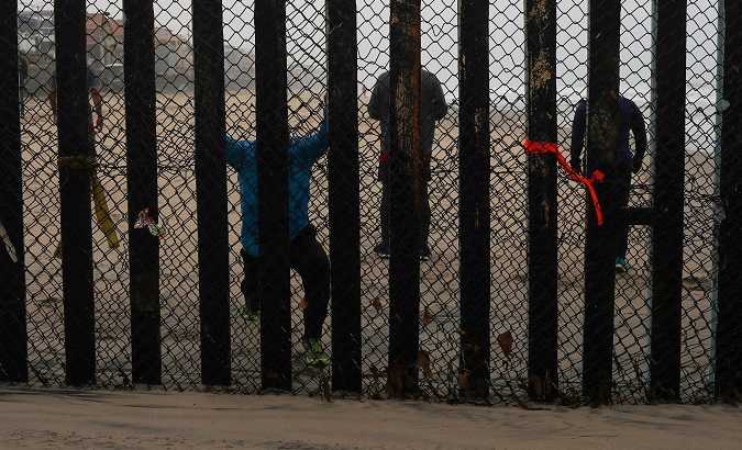 People taking part in morning workout are seen on the Mexico side of the border wall from the U.S. near San Diego, California.