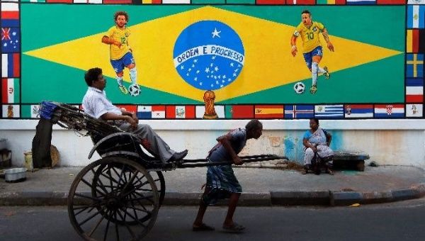 A rickshaw transports a passenger past a mural of Brazil's Neymar and Marcelo in India.