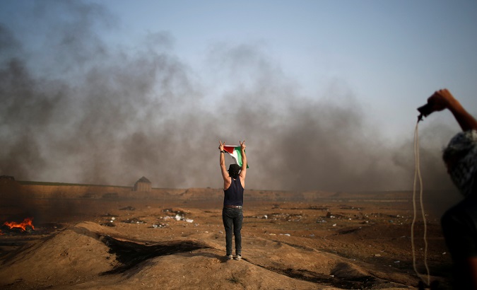 A demonstrator gestures during a protest where Palestinians demand the right to return to their homeland, at the Israel-Gaza border, east of Gaza City May 18, 2018.