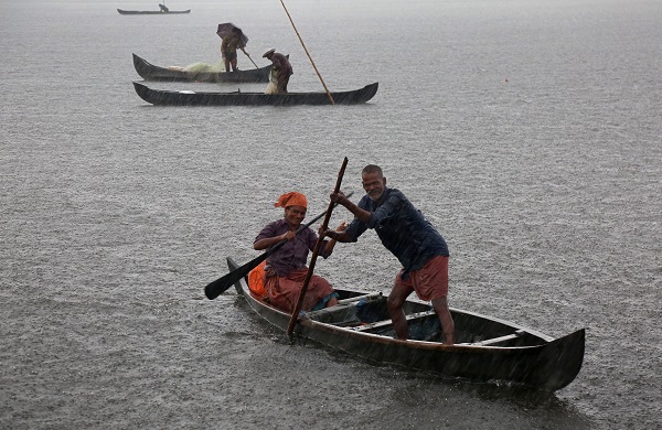 A fisherman and his wife row their boat in a fish farm as it rains heavily on the outskirts of Kochi, India, May 2018.