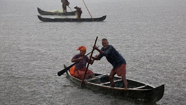 A fisherman and his wife row their boat in a fish farm as it rains heavily on the outskirts of Kochi, India, May 2018.