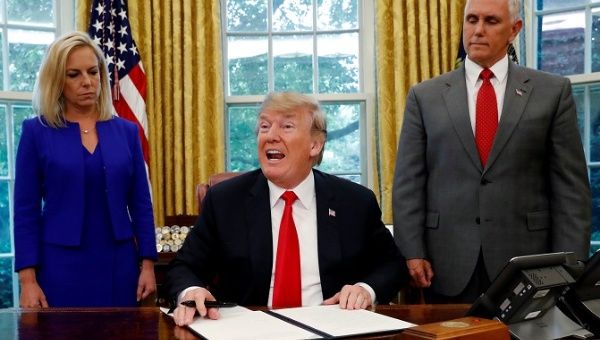 U.S. President Donald Trump (C) signs an executive order to keep migrant families together as they enter the United States.