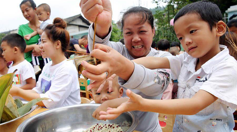 La gastronomía es fundamental en el evento, por lo que los niños del jardín Ruizhi en Liping, provincia de Guizhou (oeste), aprenden a preparar Zongzi, plato en forma de pirámide con arroz glutinoso enrollado en hojas de bambú o de caña.