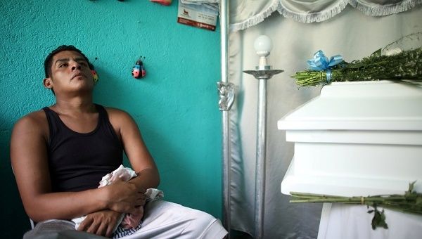 Nelson Gabriel Lorio Sandoval sits next to the coffin of his one-year-old son, Teyler, killed by a stray bullet in Managua.