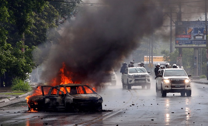 Riot police officers travel past a burning car during clashes with the anti-government protesters in Managua, Nicaragua May 28, 2018.