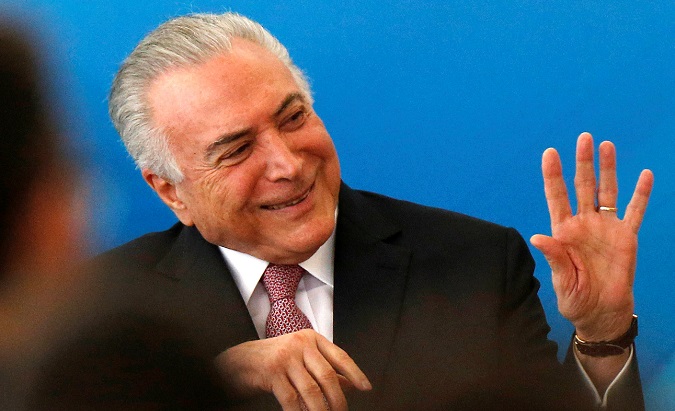Brazil's President Michel Temer smiles and waves after issuing two decrees.