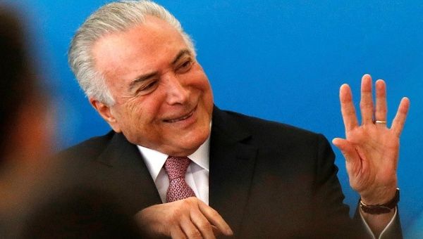 Brazil's President Michel Temer smiles and waves after issuing two decrees.