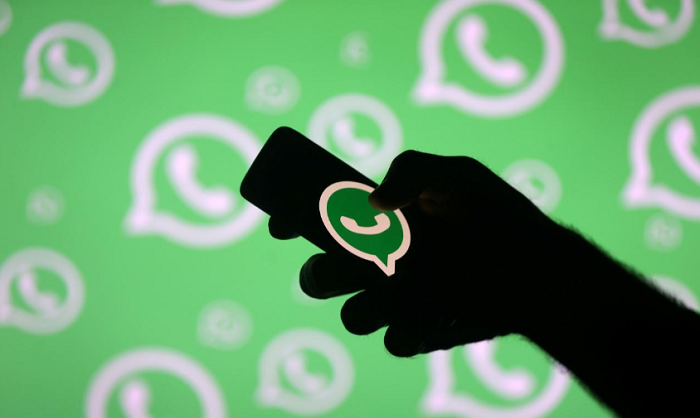 A man poses with a smartphone in front of displayed Whatsapp logo in this illustration Sept. 14, 2017.