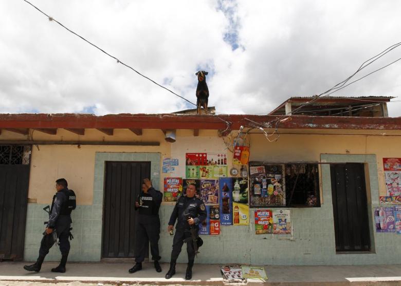Police officers stand guard on a street while colleagues help an elderly couple move their belongings in Tegucigalpa, Honduras August 10, 2014.