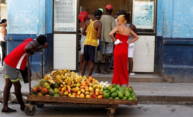 A man pushes a cart with fruits in front of a shop, as a picture of the former Cuban President Raul Castro is seen on the wall, in Havana, Cuba July 21, 2018.