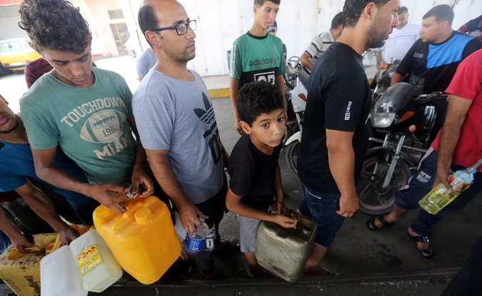 Palestinians wait to fill containers with fuel after Israel stopped the transfer of fuel and cooking gas into Gaza