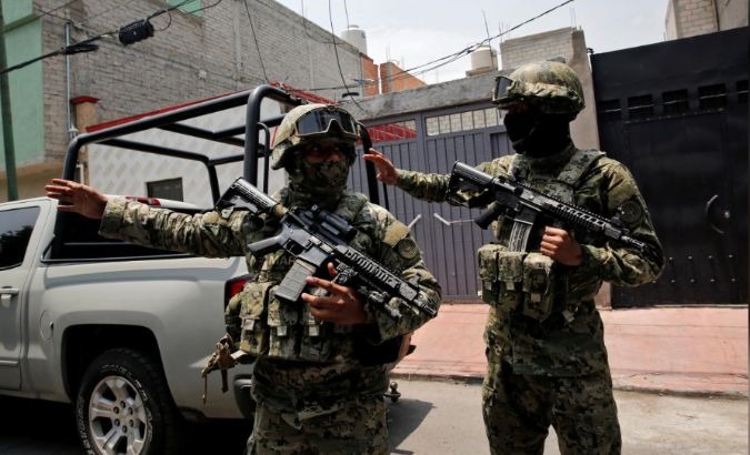 Mexican marine soldiers stand guard outside a house after suspected gang members were killed.
