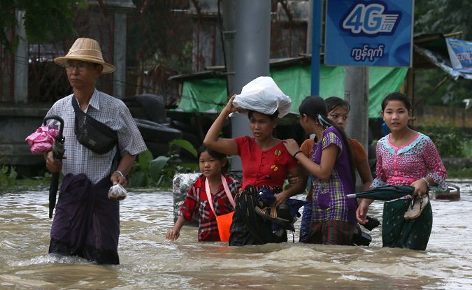 People wade through a flooded street in Bago, Myanmar, July 27, 2018. Picture taken July 27, 2018.