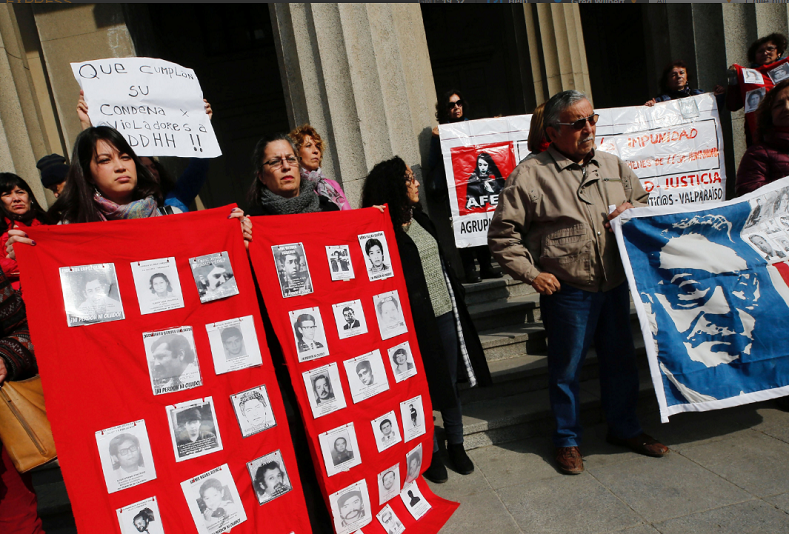 Human rights activists with images of missing people take part in a protest against the decision of the Supreme Court to grant parole to human right abusers during Chilean dictatorship, in Valparaiso, Chile August 1, 2018 