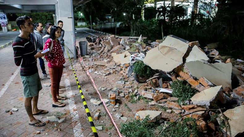 Dos jóvenes observan la destrucción que el terremoto de magnitud 7.0 dejó en el estacionamiento de un centro comercial.