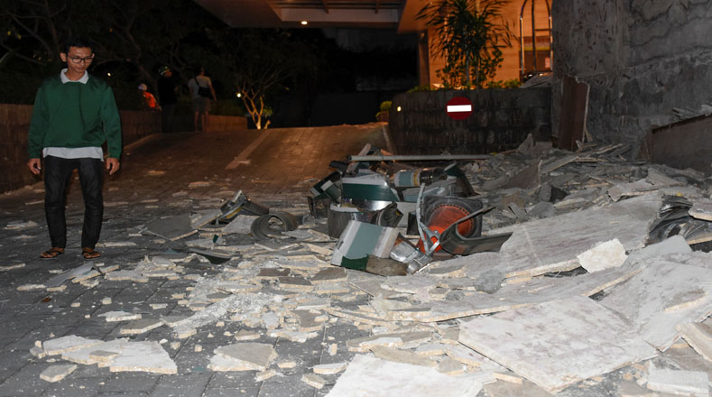 Un hombre camina entre los escombros que cayeron de un letrero afuera del hotel Santika.