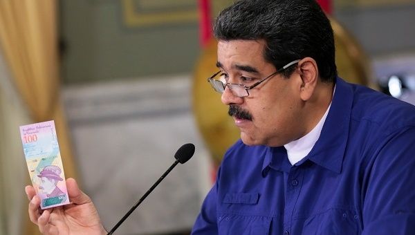 Venezuela's President Nicolas Maduro holds a bank note of the new national currency, the 'Bolivar Soberano' (Sovereign Bolivar).