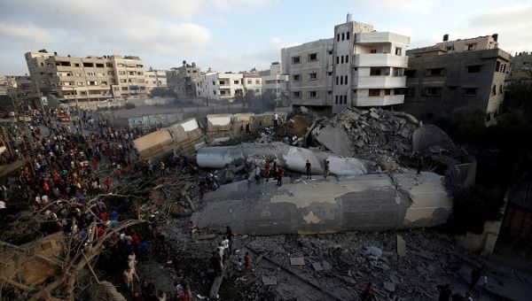 Palestinians gather around a building after it was bombed by an Israeli aircraft, in Gaza City August 9, 2018