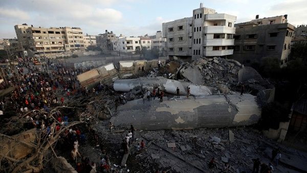 Palestinians gather around a building after it was bombed by an Israeli aircraft, in Gaza City August 9, 2018.