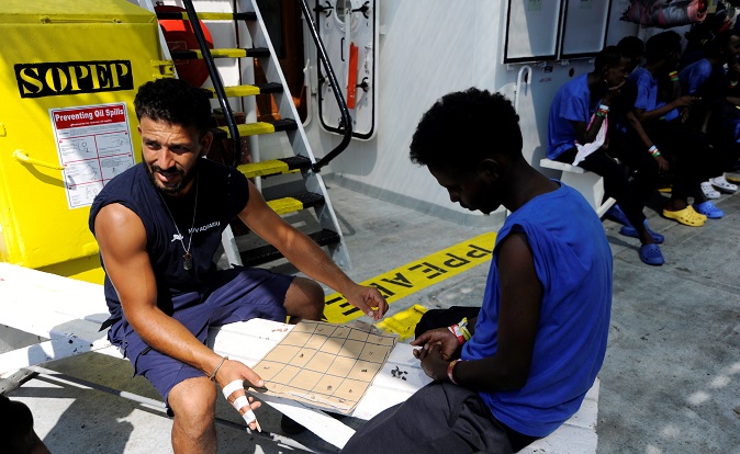 A member of SOS Mediterranee plays chess with a migrant on board the MV Aquarius, in the Mediterranean Sea, between Malta and Linosa, August 14, 2018