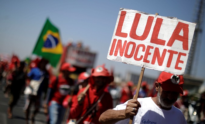 A man participating in the march to support Lula's candidacy holds a placard reading 'Lula innocent.'