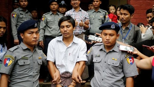 Detained Reuters journalist Kyaw Soe Oo is escorted by police after a court hearing in Yangon, Myanmar, August 20, 2018. 