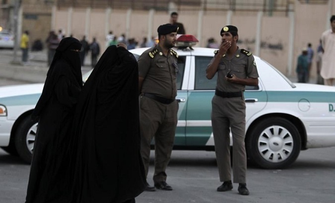Women walk by policemen in Riyadh, Saudi Arabia.