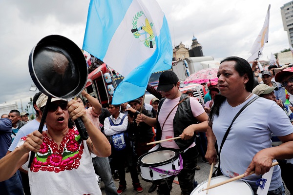 A woman hits a pan as others play drums during a protest to demand the resignation of Guatemala's President Jimmy Morales in Guatemala City, Guatemala September 12, 2018. 
