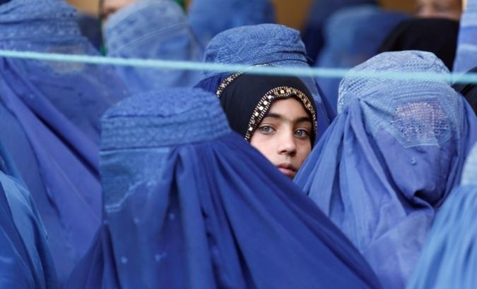 A girl looks on among Afghan women lining up to receive relief assistance in Jalalabad, Afghanistan, June 11, 2017.