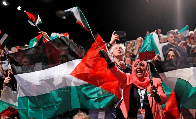 Delegates in the audience wave Palestinian flags and banners at the annual Labour Party Conference in Liverpool, Britain, Sept. 25, 2018.